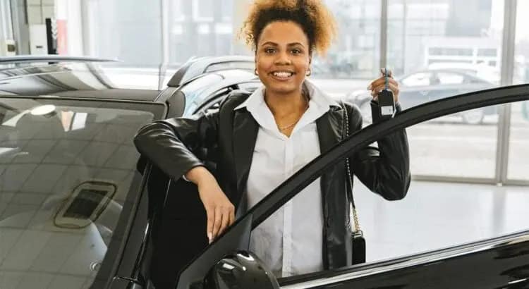 Une jeune femme dans une concession qui est heureuse après l'achat de sa voiture