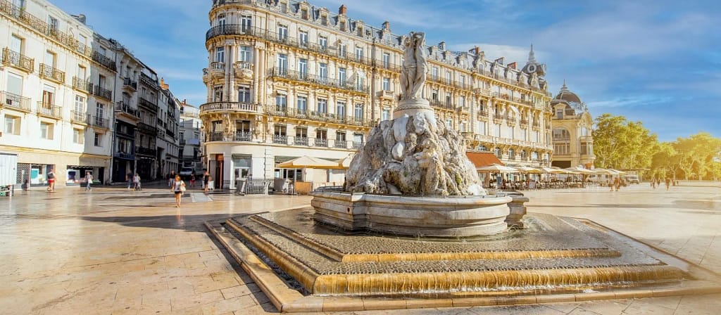 Au premier plan, une fontaine célèbre de la ville de Montpellier avec en fond la ville.