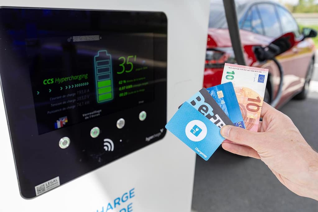 Une personne montre les différnts moyens de paiement à une borne de recharge