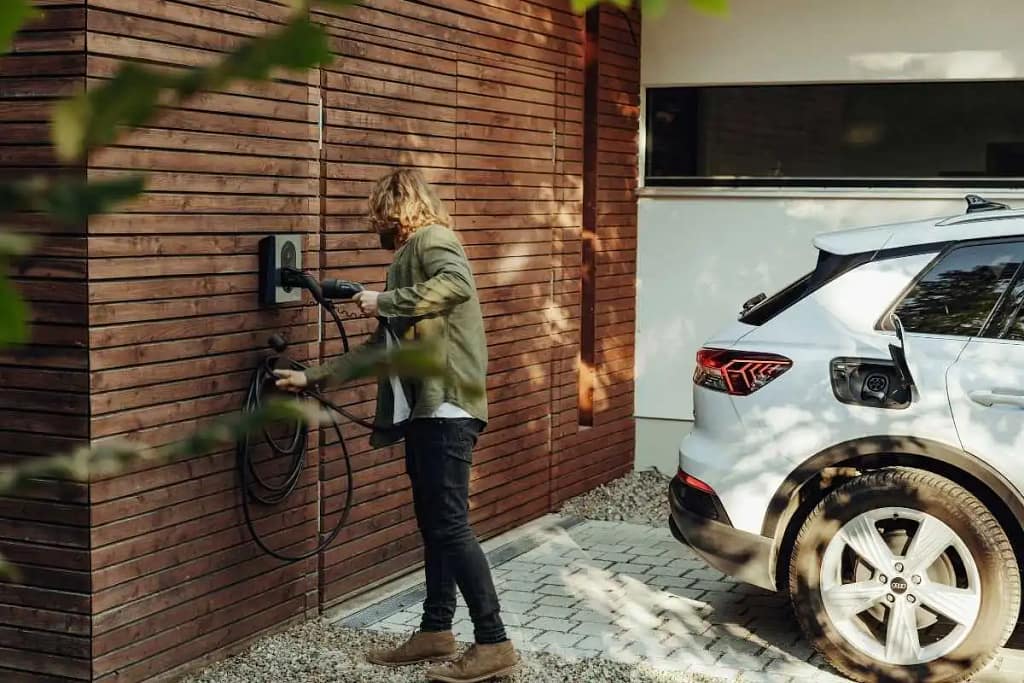 Un homme branche sa voiture sur une wallbox mural