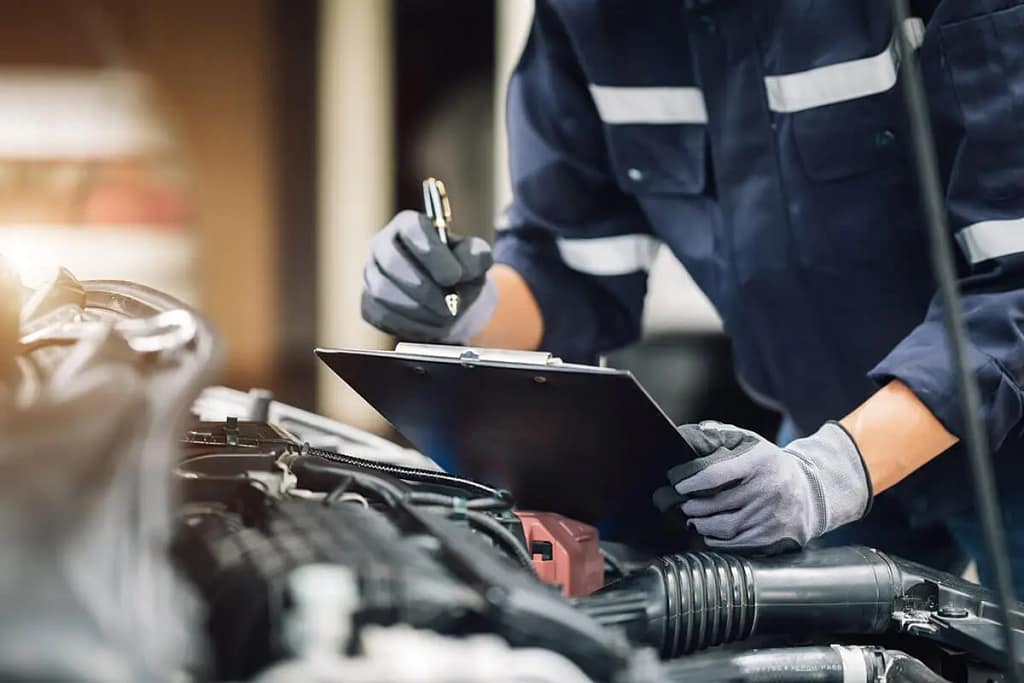 Un mécanicien procède au contrôle d'un véhicule électrique en vérifiatn une check list