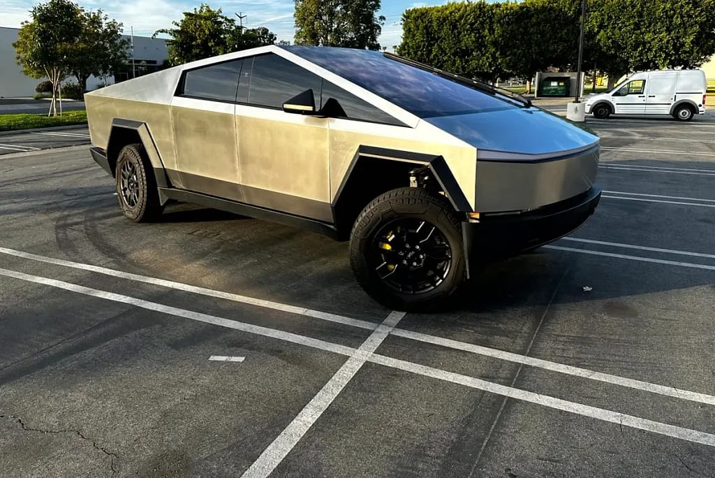 Un modèle Cybertruck de Tesla sur un parking avec d'autres véhicules en arrière plan