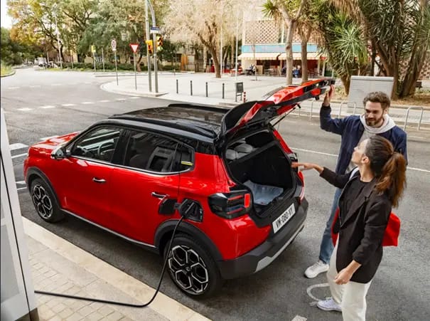 Un jeune couple charge un véhicule électrique rouge en cours de recharge