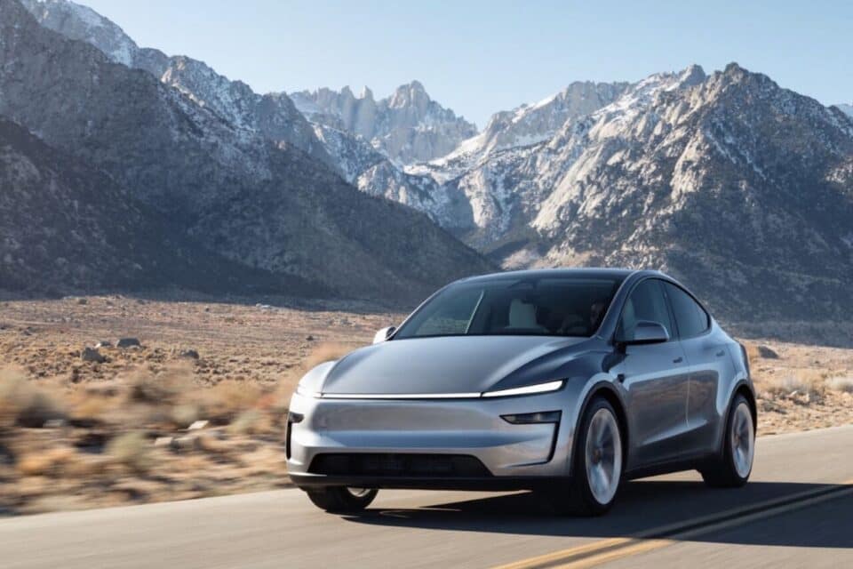 Une Tesla Model Y sur une route de campagne avec des montagnes en arrière plan